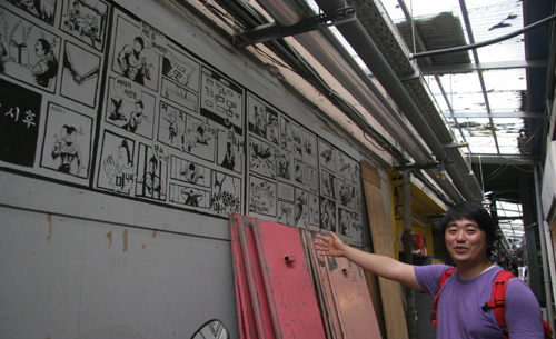 조한솔 ‘동네방네’ 대표가 낭만시장 골목에 그려진 만화 벽화를 설명하고 있다.