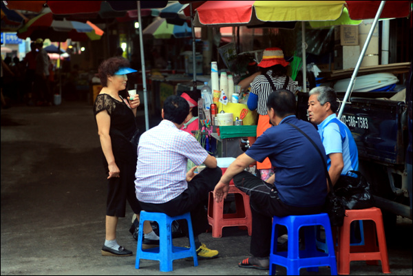 시장 상인들이 모여앉아 가판 커피를 마시며 담소를 나누고 있다.