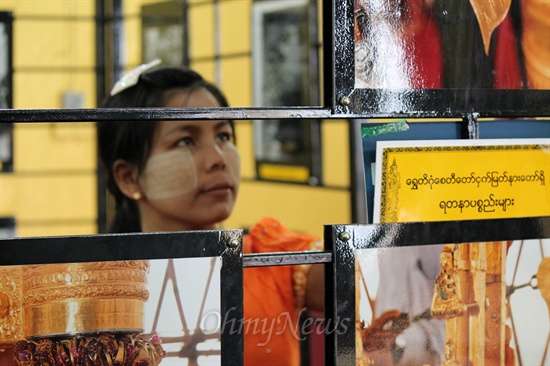 미얀마 양곤에 있는 쉐더공 파고다 내에서 열리고 있는 쉐더공 파고다 사진전을 관람하고 있는 미얀마 여인. 얼굴에는 미얀마 전통 화장품이 타나카를 바르고 있다. 