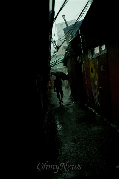 2013년 8월 6일 낮 1시께 영등포 쪽방촌에 폭우가 쏟아졌다. 이사를 하던 한 주민이 우산을 쓰고 발길을 재촉하고 있다. (자료사진)
