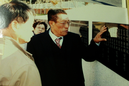 기념비에 새겨진 아버지의 이름을 만지며 눈물을 참는 김시진옹.