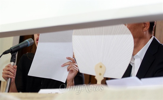 2013년 8월 19일 국정원 직원 김하영씨(왼쪽)가 국회에서 열린 국정원 댓글 의혹 사건 등의 진상규명을 위한 국정조사 청문회에 증인으로 출석해 가림막 뒤에서 미리 준비해 온 답변자료를 들고, 심문에 응하고 있다.