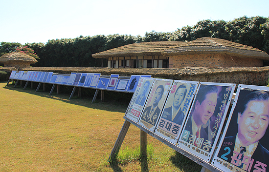 고 김대중 대통령이 출마했던 역대 선거 포스터 너머로 생가가 방문객을 맞고 있다.
