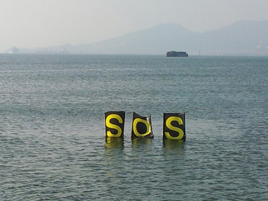 여수 해양투기선박이 다지는 광양만 바다에서 SOS글자를 들고 있는 여수환경운동연합 해양환경위원회 회원들.