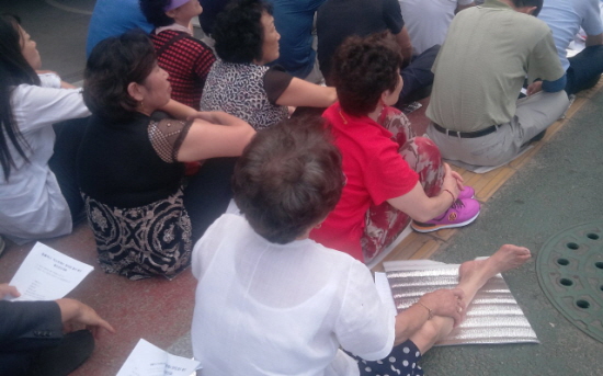 8월 27일 오후 3시 울산 동구 일산동에 있는 홈플러스 동구점 앞에서 열린 울산상인대회에 참가한 한 할머니가 다리를 뻗은 채 발언을 듣고 있다