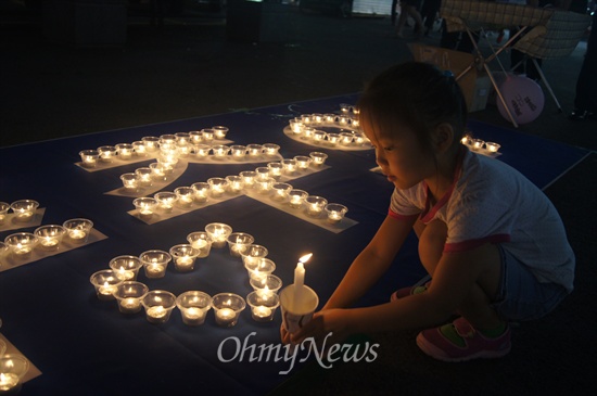 구미역 앞에서 30일 오후 열린 국정원 정치개입 규탄 촛불문화제에 부모와 함께 참석한 한 어린이가 민주주의 촛불 옆에 자신이 든 촛불을 세우고 있다.