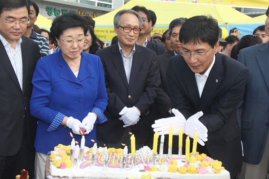 생일 기념 시루떡에 붙여 놓은 촛불이 바람에 끄지려고 하자 안희정 충남지사가 손으로 바람을 막고 있다.