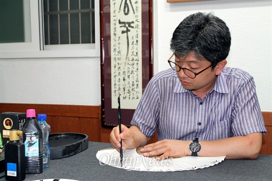 작업실 '무명각'에서 부채에 다산 선생의 글을 쓰고 있는 김성태 서예가