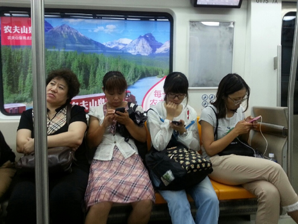 스마트폰에 눈을 떼지 못하는 젊은 여성과 사뭇 다른 중년여성의 또 다른 시선이 묘하게 오버랩. 중국 지하철의 한 풍경.