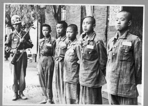 국군 헌병이 카빈소총을 든 채 소년 인민군 포로들을 감시하고 있다(1950. 8. 9.).