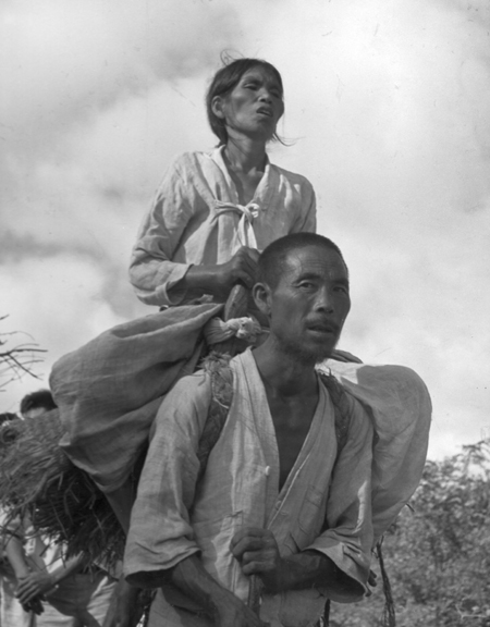 한 남정네가 병중인 시각장애인 아내를 지게에 지고 피난가다(1950. 9.).