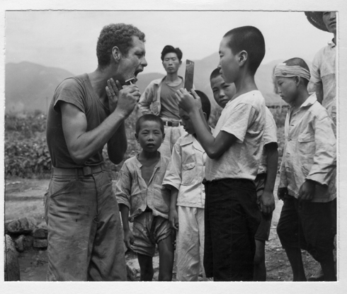한 소년이 거울을 들고 유엔군 병사의 면도를 도와주고 있다(1950. 8. 22.).