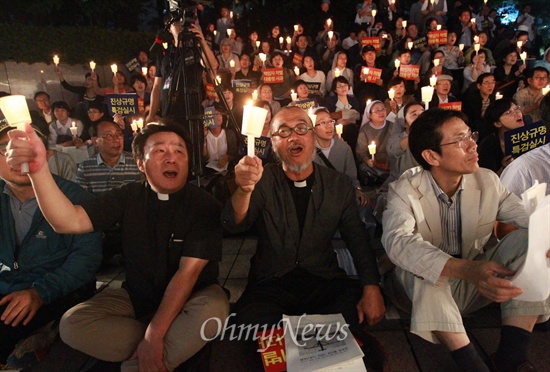 지난 11일 오후 서울 중구 파이낸스센터 앞에서 열린 '천주교 평신도 1만인 시국 기도회'에 문규현 신부와 신도, 수녀들이 참석해 국정원 대선 개입의 진상규명과 책임자 처벌을 요구하며 촛불을 들어보이고 있다.