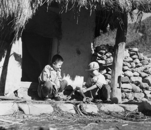한 시골 초가집 양지바른 처마 밑에서 두 소년이 정답게 이야기를 나누고 있다(1951. 11. 18.). 