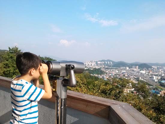 강남정을 찾은 한 아이가 망원경으로 순천 시내를 내려다보고 있다. 