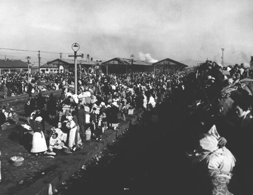 인천시민들이 플랫폼을 가득 메운 채 피난열차를 기다리고 있다. 선로 위의 무개화차에도 피난민들로 가득 찼다(인천, 1951. 1. 3.).