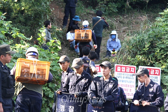  한국전력공사가 1일 밀양 송전탑 공사 재개를 위한 사전 준비작업에 들어갔다. 사진은 1일 오후 126번 철탑 부근에서 경찰이 배치된 가운데, 작업인부들이 물품을 지고 옮기는 모습.