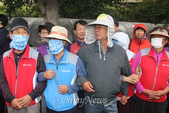  2일 대규모 공권력이 투입된 속에 한국전력공사가 송전탑 공사를 재개한 가운데, 밀양시는 단장면 단장리 소재 '765kv 신고리-북경남 송전선로 4공구 건설공사 자재 적치장' 건너편에 있는 움막을 철거하기 위해 행정대집행에 나섰다. 사진은 밀양시청 공무원이 행정대집행에 나서자 주민들이 스크럼을 짜고 대처하는 모습.