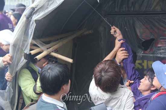  2일 대규모 공권력이 투입된 속에 한국전력공사가 송전탑 공사를 재개한 가운데, 밀양시는 단장면 단장리 소재 '765kv 신고리-북경남 송전선로 4공구 건설공사 자재 적치장' 건너편에 있는 움막을 철거하기 위해 행정대집행에 나섰다. 사진은 밀양시청 공무원들이 움막의 일부 시설물을 뜯어내자 문정선 밀양시의원이 움막에 매달려 있던 철사를 붙잡으며 자해를 시도하는 모습.