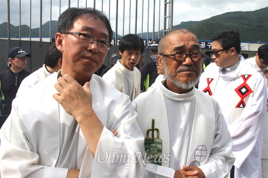  한국전력공사가 밀양 송전탑 공사를 재개한지 엿새째인 7일 오후 천주교 정의구현사제단은 밀양시 단장면 단장리 소재 '송전선로 공사장비 적치장' 앞에서 "밀양 765kV 송전탑 건설 반대 현장미사"를 올렸는데, 대표인 나승구 신부가 문규현 신부와 함께 서 있다.