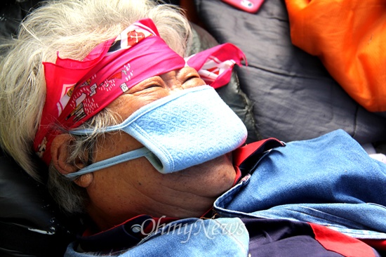 밀양 송전탑 공사 재개로 주민과 경찰, 한국전력공사 직원 사이에 충돌하는 상황이 계속 벌어지고 있다. 사진은 한 할머니가 산속 임도에서 농성하다 지쳐 쓰러져 누워 있는 모습.