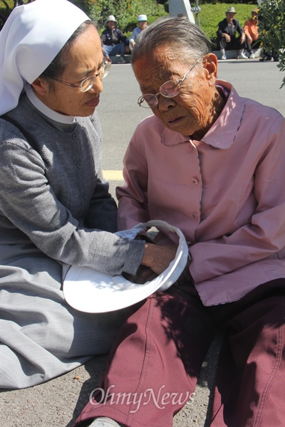 밀양시 상동면 도곡마을에 사는 김말해(86) 할머니가 12일 오전 밀양시청 앞에 나와 송전탑 공사 반대를 호소하며 울고 있다. 사진은 한 수녀가 다가와 할머니를 달래는 모습.