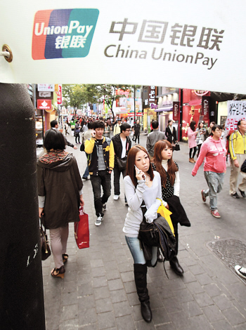 서울 명동에 걸린 중국은련카드 광고 아래를 지나다니는 사람들