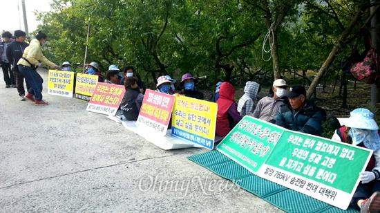  15일 밀양 송전탑 반대 주민들이 단장면 바드리마을 입구에 레미콘 차량 출입을 막겠다며 목에 쇠사슬을 묶어 농성하고, 다른 주민들은 피켓을 들고 앉아 있다.