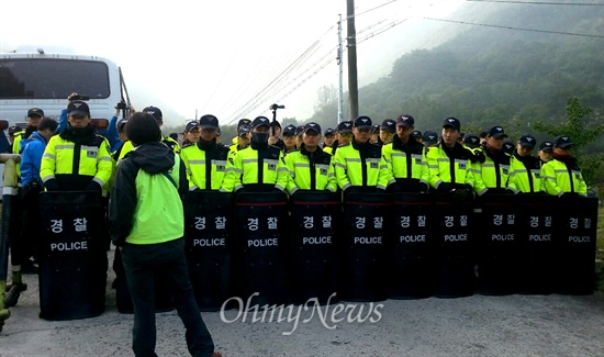  15일 밀양 송전탑 반대 주민들이 단장면 바드리마을 입구에 레미콘 차량 출입을 막겠다며 목에 쇠사슬을 묶어 농성하고 있는 속에, 경찰이 현장에 배치되어 있다.