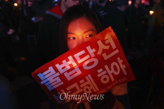 26일 오후 서울역광장에서 열린 '국정원 선거개입 및 노동탄압 규탄 범국민촛불대회'에 참석한 시민이 '불법당선 박근혜 하야'가 적힌 피켓을 들고 있다.