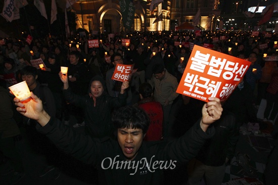 26일 오후 서울 용산구 서울역 앞에서 국정원 선거개입과 노동탄압을 규탄하는 촛불 집회에 참석한 시민이 '박근혜 하야하라'가 적힌 피켓과 촛불을 들고 마지막 공연순서의 노래를 따라 부르고 있다. 