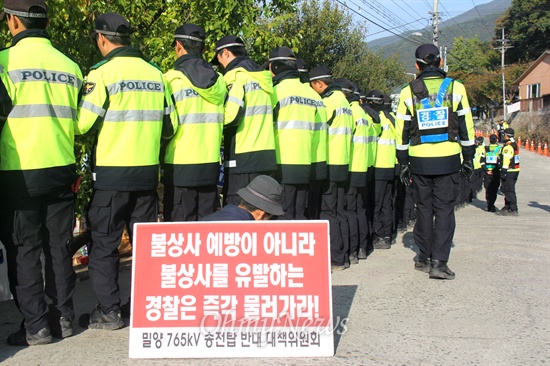 한국전력공사가 밀양 송전탑 공사를 계속하고 있는 속에, 주민들은 공사를 막기 위한 농성을 계속하고 있다. 사진은 28일 오전 한 시민이 밀양시 단장면 바드리마을 입구 진입로에서 경찰 뒤편에 앉아 피켓을 들고 있는 모습.