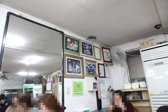 이 집이 소개된 TV화면이 캡쳐된 사진들이 걸린 벽
