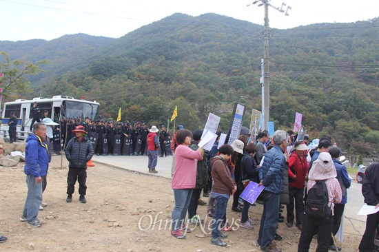  전국공무원노동조합 김중남 위원장은 전국 각 지부장들과 함께 31일 오후 밀양시 단장면 바드리마을 입구에서 기자회견을 열어 밀양 송전탑 공사 중단을 촉구했다. 사진은 기자회견하는 사람들 뒤에 경찰이 배치되어 있는 모습.