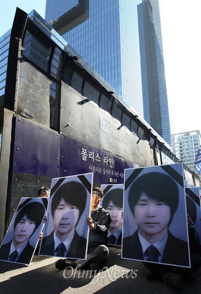  10일 서울 서초동 삼성전자 본관 앞에서 열린 '최종범열사 추모 및 삼성규탄, 열사정신계승 결의대회'에서 참가자들이 고인의 영정을 들고 삼성의 사과를 요구하고 있다. 경찰이 차벽으로 쳐 놓은 높다란 폴리스라인이 왼쪽에 보인다.