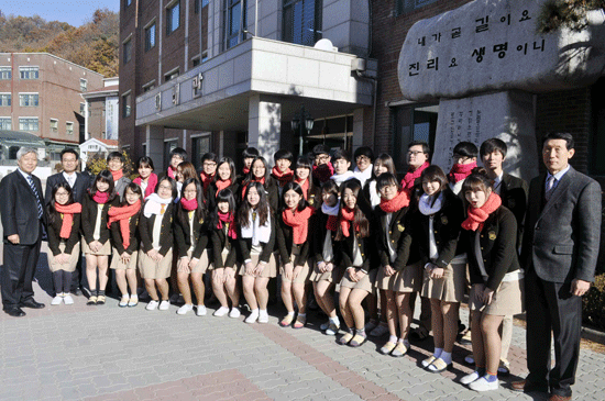 학생들이 북한에 보낼 목도리를 목에 두르고 학교 앞에서 기념사진을 촬영하고 있다
