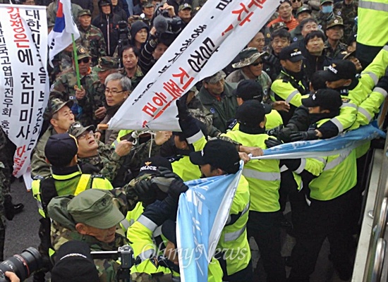 한국고엽제전우회가 25일 오후 1시 '천주교정의구현사제단 시국미사 규탄집회'를 전북 군산 수송동 성당 앞에서 열었다. 300여 명의 참가자들이 사제단 측이 건 플래카드를 뜯으려 시도하자 경찰이 이를 제지하고 있다. 