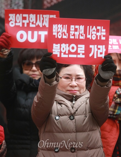 대한민국엄마부대 봉사단 회원들이 천주교정의구현사제단 신부들에게 "북한으로 가라"는 구호가 적힌 피켓을 들고 있다.