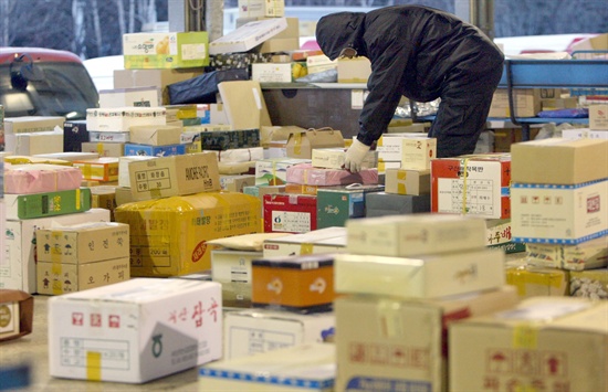 지난 2013년, 설연휴를 일주일여 앞두고 서울 동서울우편집중국에서 우체부와 택배직원들이 가득 쌓인 우편물들을 분류·정리하고 있는 모습. 