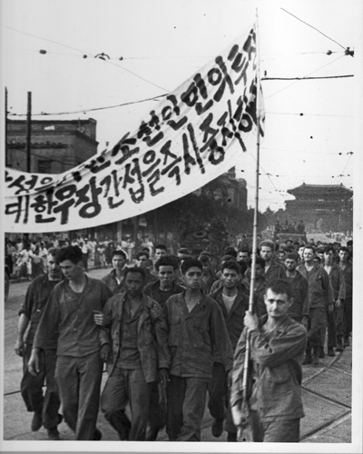 유엔군 포로들이 반전 플래카드를 들고 시가지를 행진하고 있다(서울, 1950.). 