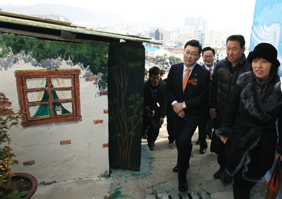  5일 박영빈 경남은행장이 ‘가고파 꼬부랑길 벽화마을 준공식’에 참석한 내외빈과 함께 마을을 둘러보고 있다.