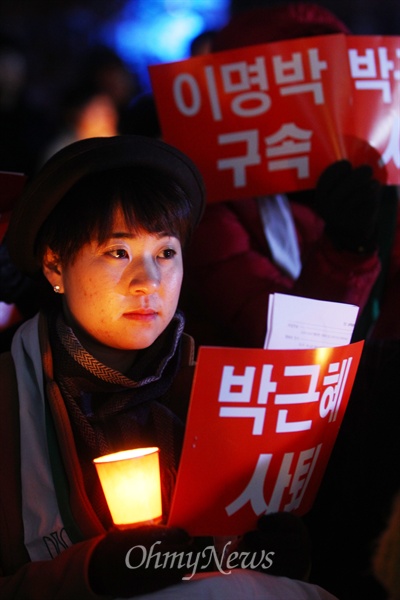 6일 오후 서울 중구 서울파이낸스센터 앞 계단에서 열린 '이명박 구속 및 박근혜 사퇴'를 위한 시국기도회에서 한 참가자가 촛불과 '박근혜 퇴진' 손피켓을 들고 있다.