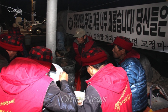 '음독 자살'했던 밀양 송전탑 공사 반대 주민 고 유한숙(74살) 할아버지의 시민 분향소가 영남루 맞은편 밀양교 옆 시계탑 아래에 설치되어 있다. 11일 저녁 주민들이 시민단체인 '너른마당'에서 가져온 밥을 나눠 먹고 있다.