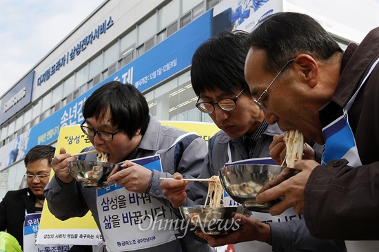 전국금속노동조합(아래 금속노조) 광주전남지부와 '삼성의 사회적 책임을 촉구하는 시민모임'이 12일 낮 12시 '삼성 앞마당'에서 국수를 말아먹었다. 이들은 평범한 집회 대신 대중의 눈길을 끌기 위한 독특한 방법을 선택해 삼성의 치부를 알렸다. 집회에 참석한 금속노조 삼성전자서비스지회 동광주센터 노동자가 광주 북구 삼성전자서비스 동광주센터 앞에서 국수를 먹고 있다.  