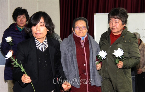 일본군위안부할머니와함께하는 마산창원진해시민모임이 12일 저녁 창원노동회관 대강당에서 연 "일본군 위안부 희생자 위령제"에서 참가자들이 헌화를 하기 위해 국화꽃을 들고 단상에 오르고 있다.