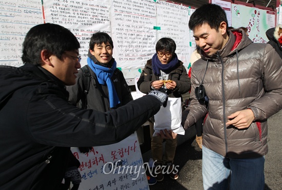 <안녕들 하십니까?> 대자보를 학내 게시판에 붙인 주현우씨(고대 경영학과, 가운데)와 학우들이 13일 오전 서울 성북구 안암동 고려대 정경대 후문에서 철도민영화 반대와 철도노동자들의 대량 직위해제에 대해 부당함을 알리자, 한 대학원생이 이를 응원하며 붕어빵을 사와 나눠주고 있다.