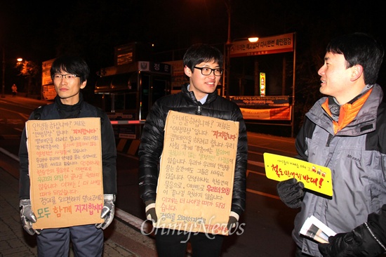  19일 저녁 창원 마산합포구 소재 경남대 정문 쪽에서 열린 "창원, 안녕하지 못한 사람들의 나들이" 행사에 참석한 사람들이 피켓을 들고 서 있다.