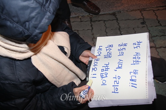  19일 저녁 창원 마산합포구 소재 경남대 정문 쪽에서 열린 "창원, 안녕하지 못한 사람들의 나들이" 행사에 참석한 사람들이 피켓을 적고 있다.