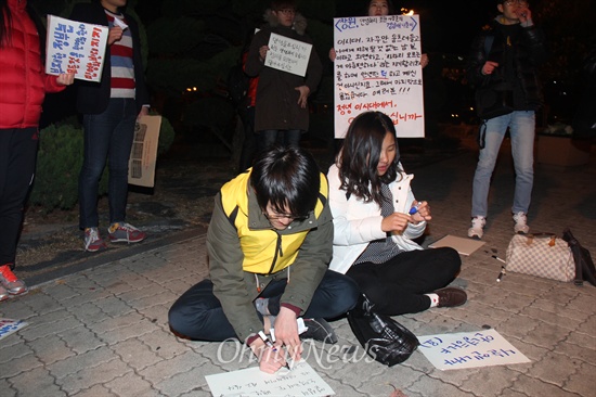  19일 저녁 창원 마산합포구 소재 경남대 정문 쪽에서 열린 "창원, 안녕하지 못한 사람들의 나들이" 행사에 참석한 사람들이 피켓을 적고 있다.