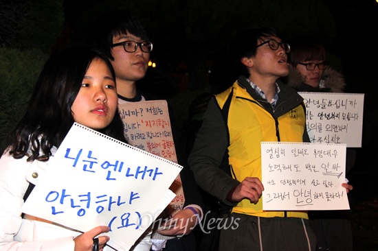  19일 저녁 창원 마산합포구 소재 경남대 정문 쪽에서 열린 "창원, 안녕하지 못한 사람들의 나들이" 행사에 참석한 사람들이 피켓을 들고 서 있다.